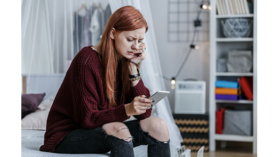 College student who appears concerned is engaging with cell phone.